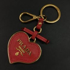 Details A Pre-Owned. Prada Heart Logo Ribbon Saffiano Leather Gold Tone Key Holder Bag Charm. The Overall Is Slightly Used, Looks Like New. There Are Cases Where There Are Small Scratches And Rubbing Etc. Although It Is Hard To See In The Photograph. The Item Is Sold In As Is Condition. Please Check The Photos For More Details. Prada Heart Bag, Keychain Designer Luxury, Luxury Red Jewelry With Heart Charm, Prada Key Ring, Luxury Leather Keychains With Interior Holder, Red Keychain, Prada Accessories, Heart Logo, Key Card Holder