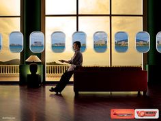 a man sitting on a couch looking out an airplane window at the ocean and sky