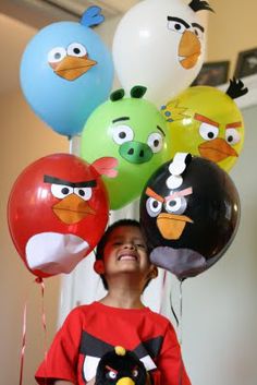 a young boy standing in front of balloons with angry birds on them