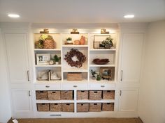 a white bookcase filled with lots of books and baskets