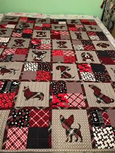 a bed with a red and black dog quilt on it's side, next to a green wall