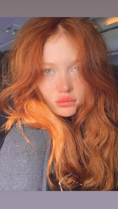 a woman with long red hair sitting in a car