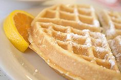 two waffles on a white plate with a lemon wedged in between them