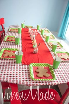 a table set up with gingerbread cookies and green cups on it for a party