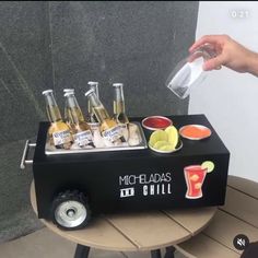 a person is pouring drinks into a cooler on a table with other beverages and condiments