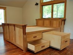 a bed with two drawers in the middle of it on a hard wood floor next to a window