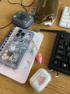 a wooden table topped with an iphone case and computer mouse next to a keyboard on top of it