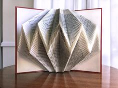 an open book with folded pages sitting on top of a table