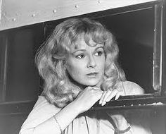 an old black and white photo of a woman leaning on a window sill looking at the camera