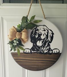 a wooden sign with a dog on it hanging from the front door, decorated with greenery and a bow