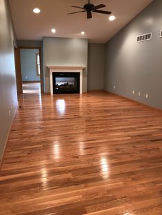 an empty living room with hard wood floors and a fire place in the fireplace area