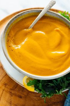 a white bowl filled with carrot soup on top of a wooden cutting board