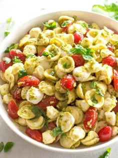 a white bowl filled with pasta salad and garnished with parsley on top