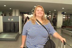 a woman is standing with her luggage at the airport and she is smiling for the camera