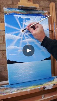 a person is painting on an easel with a paintbrush