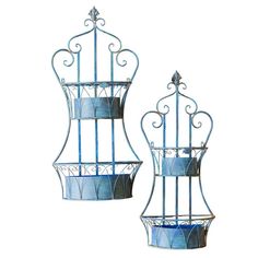 two metal planters sitting next to each other on top of a white surface with blue accents