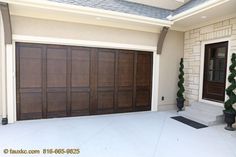 a garage door is open in front of a house with potted plants on the porch