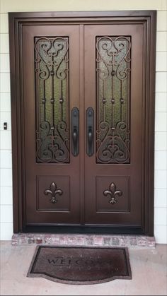 the front door to a house with two double doors and an entry mat on the ground