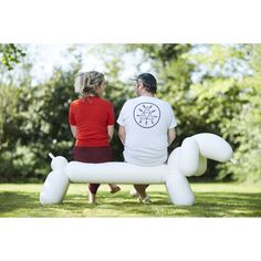 a man and woman sitting on an inflatable balloon dog, looking at each other