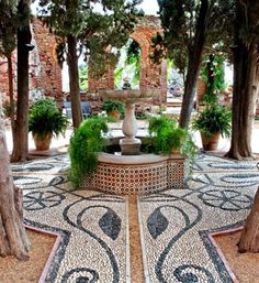 a fountain surrounded by potted plants and trees