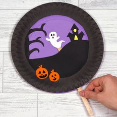 a hand holding a paper plate with halloween decorations on it