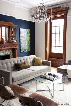 a living room filled with furniture and a chandelier hanging from the ceiling over a fire place