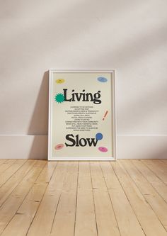 a poster is sitting on the floor in front of a white wall that says living slow