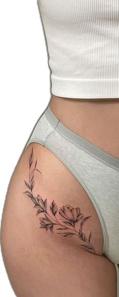 a woman's stomach with flowers and leaves tattoo on her side ribcage