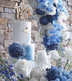 a blue and white wedding cake with the word aster on top, surrounded by flowers