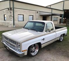 a white pickup truck parked in front of a building with grass and dirt on the ground