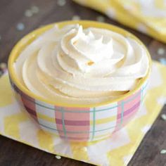 a bowl filled with whipped cream sitting on top of a yellow and white checkered napkin