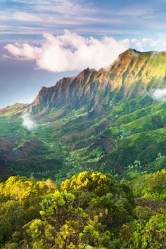 the mountains are covered in green vegetation and clouds above them, as well as some trees