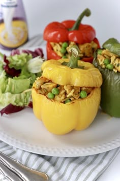 stuffed bell peppers on a white plate with salad in the background and bottle of mustard