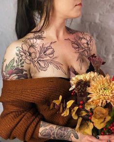 a woman with tattoos holding a bouquet of flowers