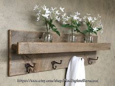 three mason jars with flowers in them are hung on a wooden shelf above a towel rack