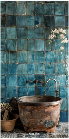 an old bathtub sitting in front of a blue tiled wall with flowers on it