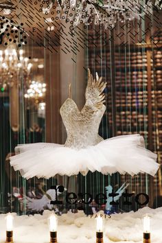 a white dress hanging from the ceiling in front of a chandelier filled with glass beads