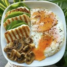 a person holding a plate with eggs, mushrooms, and other food items on it