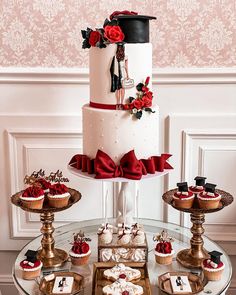 a table topped with lots of cupcakes and cakes covered in red ribbon bows