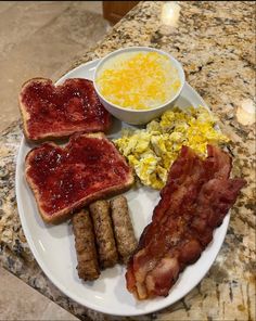 a plate with bacon, eggs, toast and other breakfast foods on it sitting on a marble counter top