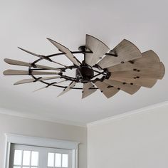 a ceiling fan with wooden blades hanging from it's center point in a living room