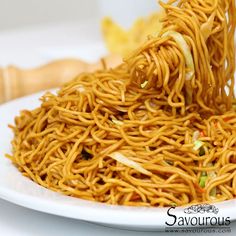 noodles being lifted from a white plate with chopsticks