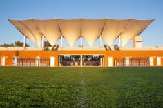 a building with large white umbrellas over it's windows on top of a green field