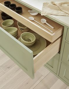 an open drawer in a kitchen filled with plates and bowls on top of a counter