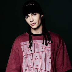 a young man with dreadlocks wearing a red shirt and black beanie hat