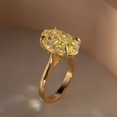 a fancy yellow diamond ring on a white surface