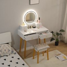 a bedroom with a bed, desk and mirror on it's side table in front of a window