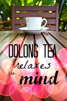 a table with a coffee cup and saucer on it that says, oolong tea relaxes the mind