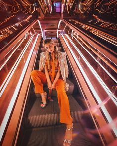 a woman sitting on top of an escalator with lights in the back ground