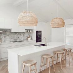 a kitchen with white counter tops and wooden stools